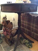 Full view of the vintage round pedestal side table showing tabletop, drawer and leg design near sofa and floor decor.