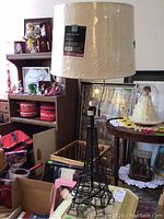 Photo of black metal wireframe Eiffel Tower floor lamp with cream satin shade, showing the full lamp and shade details.