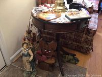 Statues and wood Welcome sign visible on floor and chair beside table.