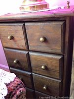 View of one wooden cabinet showing six drawers with round wooden knobs.