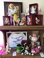 Top shelf display including 14" Alice doll, White Rabbit plush, boxed figurines, Tweedledee & Tweedledum, Mad Hatter bust
