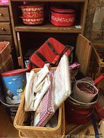 Photo showing assortment of kitchen and household items including metal pots, baskets, cloths, and insulated bag.