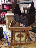 Overall view of painted wood hamper, woven basket on top, and wooden crate below on carpet with floral pattern