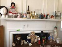 Full view of the items including stuffed bears, figurines, doll, bottle, eagle figurine, and rabbit dome figurine on and near a fireplace mantle.