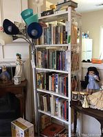 Full white metal shelving unit filled with hardback books and one boxed audiobook set visible on top right