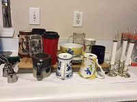 Various mugs, ceramic and glass, some with designs, along with travel mugs and small bowls