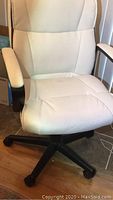 White padded office chair from front showing seat, armrests, and wheeled base with some soiling on the seat.