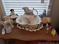 Photo showing entire lot including pitcher and basin, various Goebel figurines, Disney unicorn figurine, and Disney salt and pepper shakers on a wooden surface with lace doily.