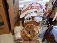 Woven baskets stacked near handsewn quilt and blankets under window.