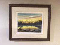 Framed oil painting showing landscape scene at sunset with pond and flying birds