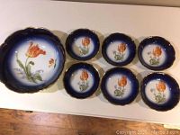 Photo showing one large and six small Bavarian bowls with floral hand-painted pattern, blue gradient background, and gold trim