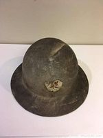 Front angle of WW2 steel helmet showing worn decal and surface wear.