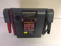 Front view shows gray jump starter with red and black clamps attached on either side, labeled 900 peak amps, Booster PAC ES 2500.