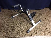 Photo showing the entire drive leg exerciser angled to display the pedal with strap and part of the frame on carpet.