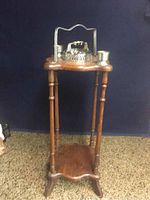 Full view of the tall wooden smoke stand with metal ashtray and match holders on top.