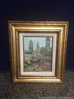 Front view of the painting in a large gold wooden frame showing Rouen street scene with several towers.
