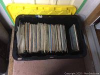 Wide view of large black plastic container filled with rows of assorted vinyl record albums with different colors and designs.