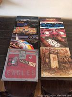 Photo showing 11 vinyl record albums laid out on a table, featuring classic rock bands such as Eagles, Def Leppard, Electric Light Orchestra, Black Sabbath, The Police, and Boston.