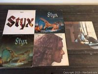 Five original vinyl albums displayed on a table: three Styx albums with various cover art and one Carole King album with a photo of Carole King and a dog.