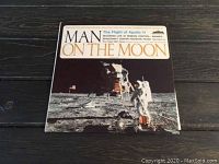 Front cover of vinyl album titled 'Man on the Moon' showing astronaut on Moon with US flag.