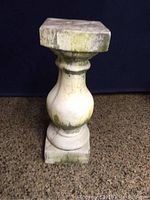 Front view of concrete column showing baluster shape and weathered surface with green patina.