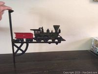 Side view showing the wrought iron train shelf mounted, highlighting the detailed locomotive and red caboose with vertical mounting rod.
