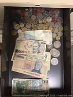 Photo showing mixed assortment of foreign currency coins and several banknotes, including noticeable bills from Brazil, Argentina, and Uruguay.
