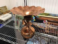 Front and side view of vintage copper night lamp showing large flared lampshade and bulbous body with attached power cord on metal rack.
