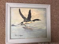 Framed 18x20 oil on board painting depicting a goose taking off from water, signed by K.C. Roger on the lower left corner.