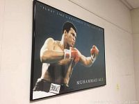 Framed Muhammad Ali boxing print viewed from an angle, showing the black frame and glass reflection.