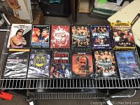 A collection of wrestling DVDs displayed on a wire rack including Bret Hart, WrestleMania 20 and 21, ECW, and Legends of Wrestling boxed sets.