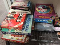 Stack of vintage board games including Mouse Rabbit, Bermuda Triangle, Cheers, and others showing titles, colorful boxes, and wear.
