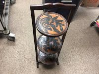 Front view of the folding shelving piece showing carved circular shelves with leaf and bird motifs.