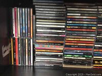 Photo showing a large collection of music CDs stacked in piles, featuring varied artists and genres with visible titles including Motown, Dave Matthews Band, Prince, and others.