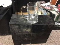 Six black boxes stacked in sets of three with a large clear glass beer mug on top. Photo to show quantity and condition.