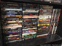 Photo showing multiple DVD titles stacked closely together, covering various action and thriller movies.
