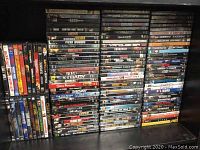 Shelf stacked with numerous DVDs arranged in vertical columns showing spine titles of action thriller movies
