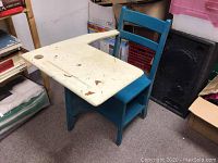 Side view of vintage blue wooden school desk with cream-colored worn desktop showing paint chipping and scratches