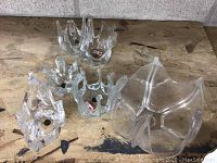 Four hand blown glass bowls of abstract shape arranged on a wooden surface, showing Canadian labels.