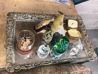 View of lot items on large ornate mirrored tray including glass butterfly dome, fish figurine, pear-shaped item, carved monkey figurine, green glass item, crystal figurine, vintage watch cases, and jewelry box.