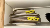 Stacks of Lenox plates labeled as 6 small plates and 8 large plates on a shelf