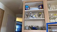 Shelf with Italian ceramic salt, pepper, oil, vinegar set with matching tray, two cat mugs, and glassware above and below.