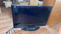 Front view of the 32-inch Insignia LCD flatscreen TV showing black screen and base stand on wooden floor.