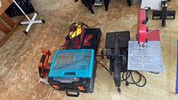 Photo showing drills, scroll saws, circular saw, and Rotozip tool arranged on floor.