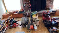 Overview of lot showing electric edger, tiller cultivator, mineral boxes and various garden and pest control tools on floor near window and brick fireplace.