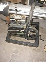 Side view of Craftsman radial arm saw showing motor, arm, and base with electrical cord and dust hose attached.
