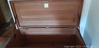 Open wooden hope chest displaying internal storage space, hinged lid, and clean interior.