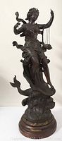 Full front view of metal statue on round wooden base