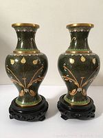 Front view of the pair of vintage cloisonne Jingfa vases on their black wood pedestal bases.