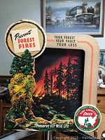 Front view of the motion light display showing printed forest fire scene, top and bottom discs with slogans